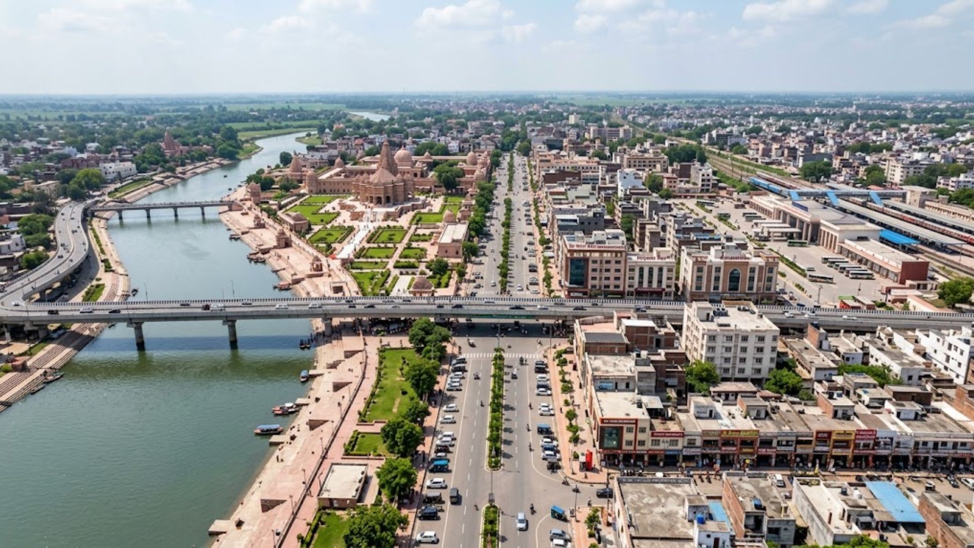 Aerial view of Ayodhya city showing the Saryu River, bridges, wide roads, temples and expanding urban infrastructure.